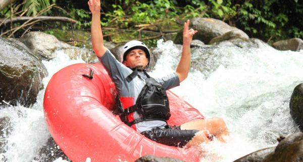 Arenal Water Activities Image: Adventurer makes peace signs from red inner tube on Sky River Drift.
